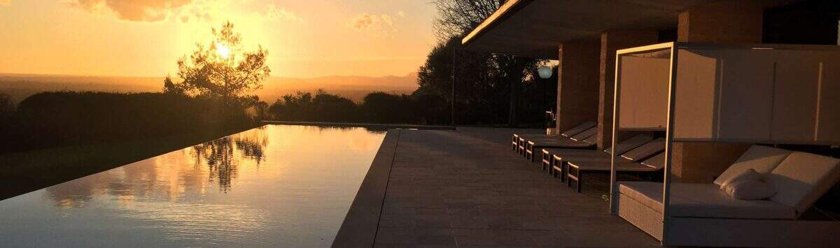 Infinity-Pool der Designer-Finca Felanitx bei Sonnenuntergang mit Loungebereich und Panoramablick