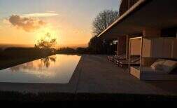 Piscina infinita de la finca de diseño Felanitx al atardecer con zona lounge y vista panorámica