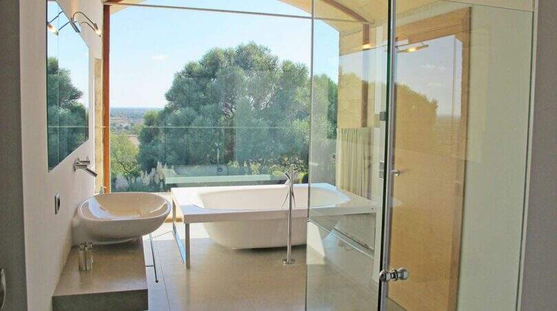 Luxusbad der Designer-Finca Felanitx mit freistehender Wanne, Glasdusche und Panoramafenster mit Gartenblick