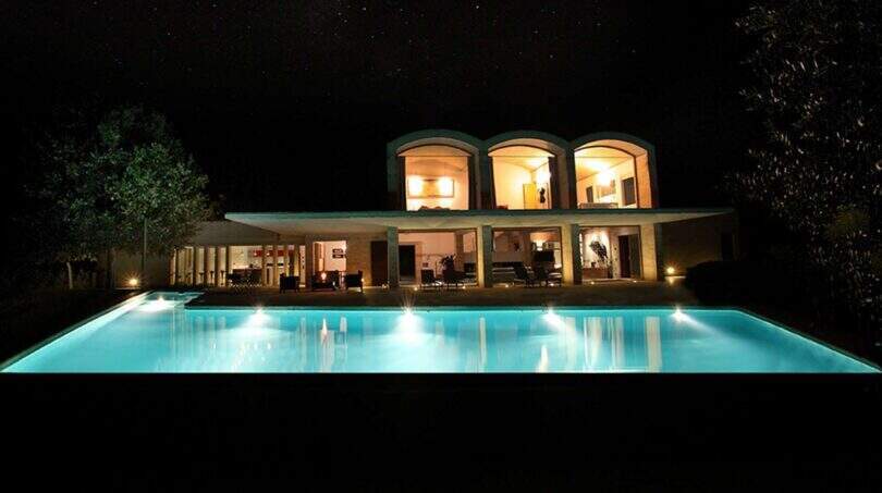 Beleuchtete Designer-Finca in Felanitx bei Nacht mit leuchtendem Pool und eleganter Außenarchitektur.