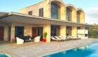 Moderne Finca in Felanitx mit großem Pool, Sandstein-Fassade und eleganten Rundbogenfenstern im Obergeschoss.