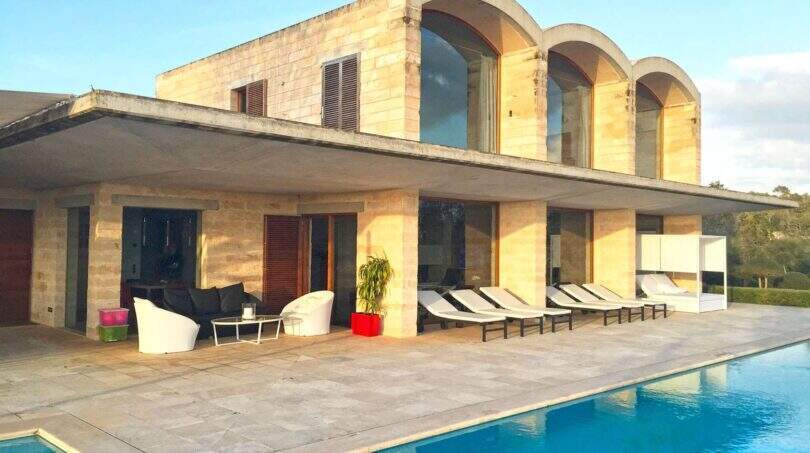 Moderne Finca in Felanitx mit großem Pool, Sandstein-Fassade und eleganten Rundbogenfenstern im Obergeschoss.