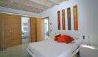 Helles Schlafzimmer der Designer-Finca Felanitx mit weißem Doppelbett, orangefarbenen Kissen und Gewölbedecke.
