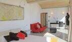Helles Schlafzimmer der Designer-Finca Felanitx mit rotem Sessel, moderner Kunst und elegantem Ambiente.