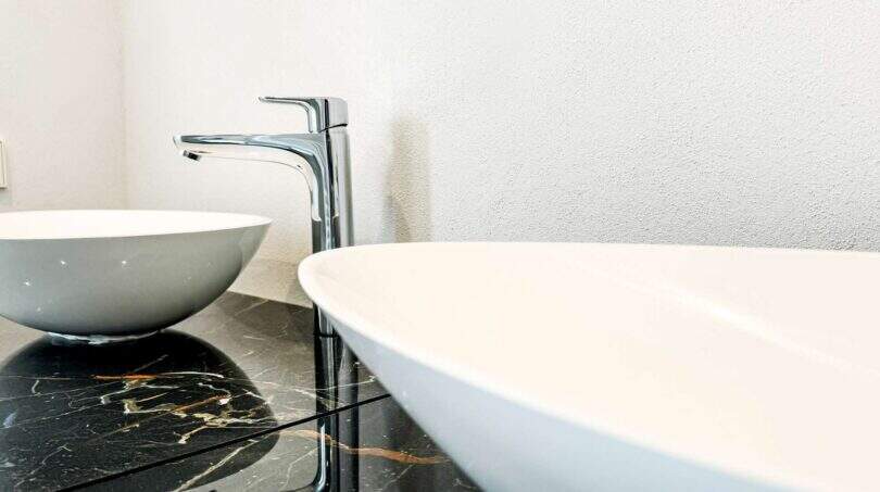 Moderno lavabo doble sobre placa de mármol negro con grifo cromado en el apartamento de lujo en Felanitx