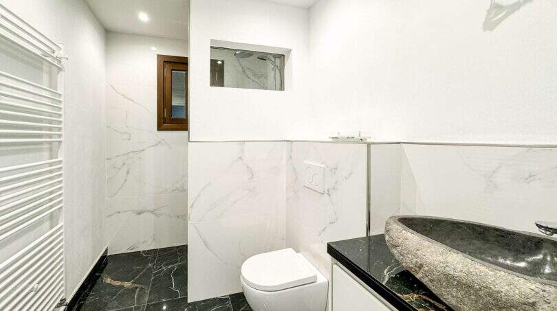 Baño moderno del apartamento de lujo en Felanitx con baldosas de mármol, lavabo de piedra natural e inodoro suspendido