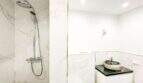 Baño moderno del apartamento de lujo en Felanitx con ducha de lluvia, paredes de mármol y lavabo de piedra natural