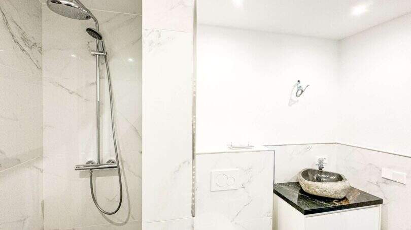Baño moderno del apartamento de lujo en Felanitx con ducha de lluvia, paredes de mármol y lavabo de piedra natural