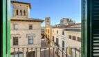 Balcón con contraventanas verdes de madera y vistas a fachadas históricas de piedra y campanarios de iglesia en Felanitx