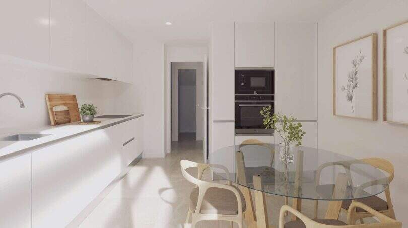 Helle Küche mit weißen Einbauschränken, Glasrundtisch und Holzstühlen in einem Neubau-Chalet in Palma de Mallorca