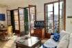 Luminosa sala de estar con sofá blanco, muebles de madera y grandes puertas de balcón con contraventanas verdes en Palma