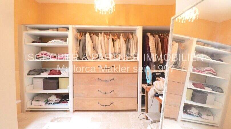 Geräumiges Ankleidezimmer mit offenen Regalen, Kleiderstange und Holzkommode im sanierten Landhaus in Port de Manacor