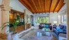 Wohnzimmer mit Holzbalkendecke, Marmorböden, blauen Sofas und Blick in den Garten – mediterrane Villa Sa Coma