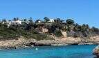 Küstenansicht von Cala Murada mit türkisblauem Meer, Felsen und Villen auf der Klippe.