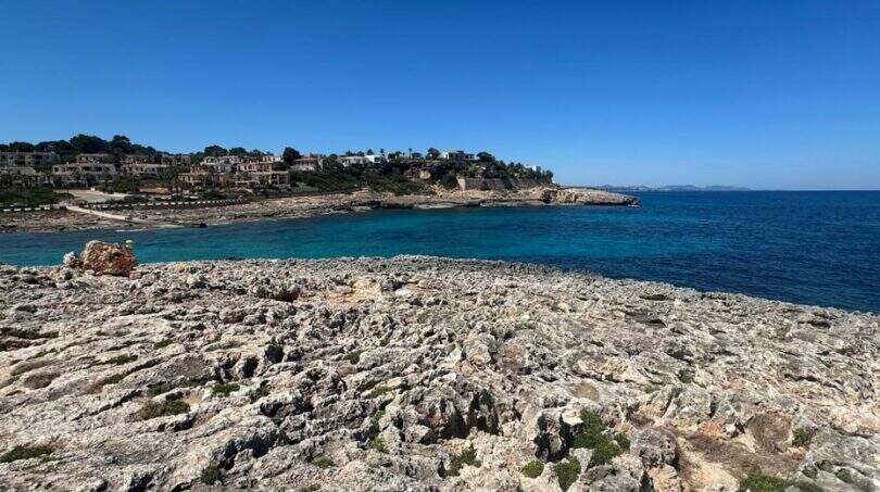 Felsige Küste mit türkisblauem Meer und Villen auf der Halbinsel in Cala Murada, Mallorca.