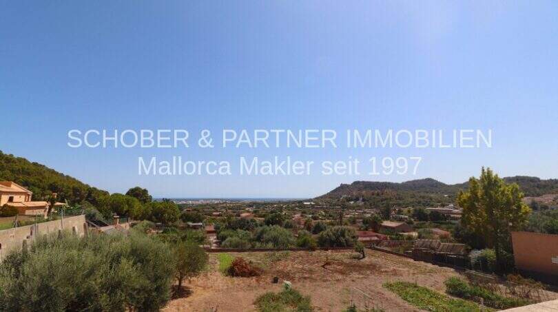 Panoramic view of Son Servera: Expansive landscape with sea view, hills and Mediterranean vegetation under blue sky.