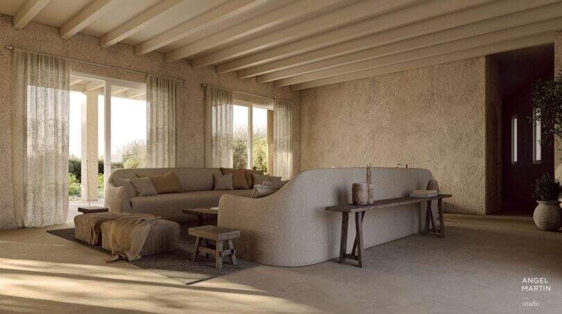 Helles Wohnzimmer der Designer-Villa Santanyí mit Rundsofa, Holzbalkendecke und Natursteinwänden.