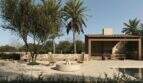 Mediterraner Außenbereich der Designer-Villa in Santanyí mit Feuerstelle, Holzstühlen und überdachtem Grillbereich.