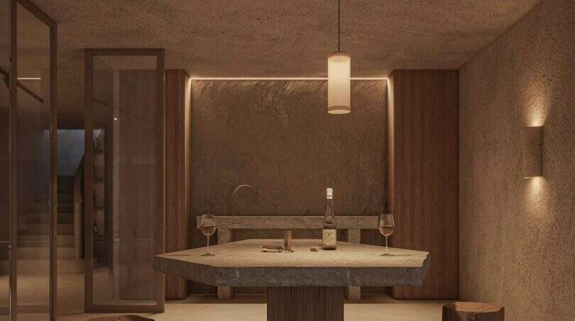 Weinverkostungsraum der Designer-Villa Santanyí mit Steintisch, Holzsockeln und warmem Ambiente