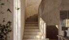 Heller Eingangsbereich der Designer-Villa in Santanyí mit geschwungener Steintreppe und Rundbogenfenster