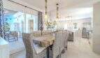 Eleganter Essbereich mit Rattanstühlen, Holztisch und offener Küche, Blick auf sonnige Terrasse in mediterraner Villa Sa Coma