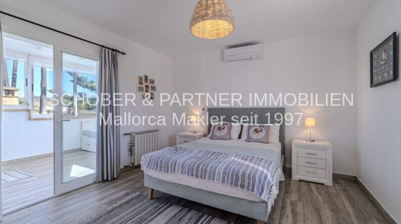 Helles Schlafzimmer der mediterranen Villa in Sa Coma mit Doppelbett, Klimaanlage und Zugang zur Terrasse.