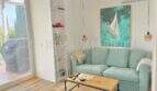 Helles Wohnzimmer mit türkisfarbenem Sofa, Segelboot-Kunstwerk und Balkonzugang in Cala d'Or
