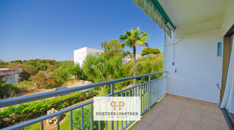 Sonniger Balkon mit Metallgeländer, Markise und Blick auf Palmen und Grünflächen in Cales de Mallorca