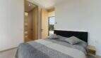 Modern bedroom with black upholstered headboard, gray bedding and access to terrace in design villa S'Alqueria Blanca