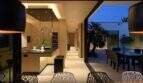 Open kitchen-living area with cooking island, design chairs and transition to illuminated terrace at night