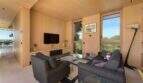 Bright living room with wooden cladding, TV, sofas and panoramic windows with sea view in S'Alqueria Blanca