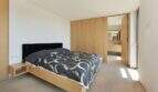 Modern bedroom with double bed, wooden built-in wardrobe and adjoining bathroom in design house Mallorca.