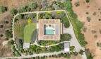 Aerial view of a modern country house in S'Alqueria Blanca with pool, garden, fruit trees and outbuildings.