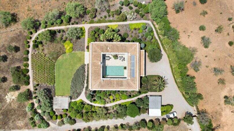 Aerial view of a modern country house in S'Alqueria Blanca with pool, garden, fruit trees and outbuildings.
