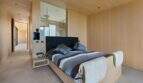 Modern bedroom with wooden cladding, black headboard, striped bedding and open shower area in S'Alqueria Blanca.