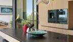 Modern designer kitchen with black granite island, built-in appliances and large windows with nature view