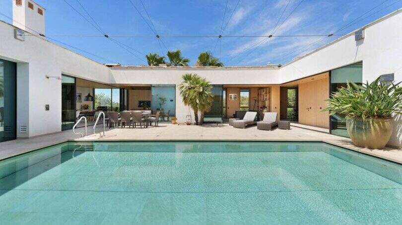 Modern design house in S'Alqueria Blanca: Large pool in the courtyard with lounge area and palm trees.