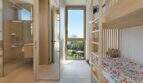 Children's room with wooden bunk bed and colorful bedding, adjacent modern glass bathroom with rain shower, garden view.