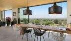 Open dining area with rustic wooden table, modern designer chairs and panoramic windows with sea view in S'Alqueria Blanca.