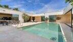 Modern courtyard pool with terrace, lounge furniture and large glass fronts in design villa S'Alqueria Blanca