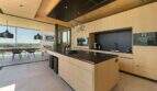 Modern design kitchen with cooking island, wooden fronts and panoramic windows with sea view in S'Alqueria Blanca