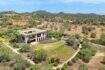 Aerial view modern design house in S'Alqueria Blanca with spacious garden, olive trees and mountain panorama.