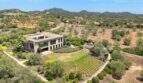 Aerial view modern design house in S'Alqueria Blanca with spacious garden, olive trees and mountain panorama.
