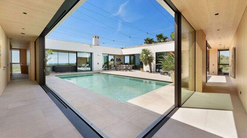 Open living area with panoramic sliding doors to the private pool and courtyard in modern design house