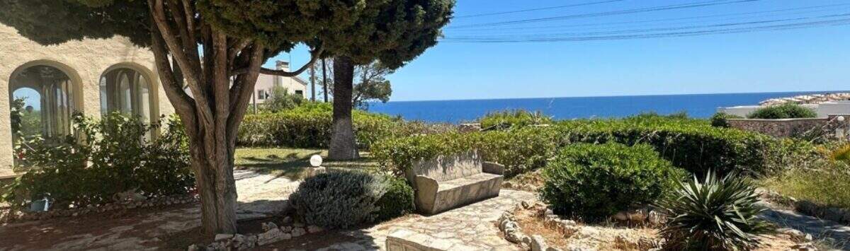 Gepflasterter Garten mit Natursteinmauer, altem Baum und Meerblick der Villa in Cala Murada