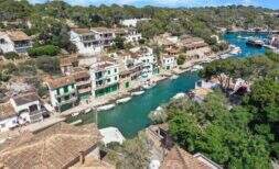Fotografía aérea del pintoresco puerto de Cala Figuera con agua turquesa, casas blancas y barcos
