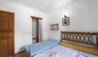 Schlafzimmer der Villa in Cala Figuera mit Doppelbett, Holzkopfteil, Einbauschrank und Wandleuchte
