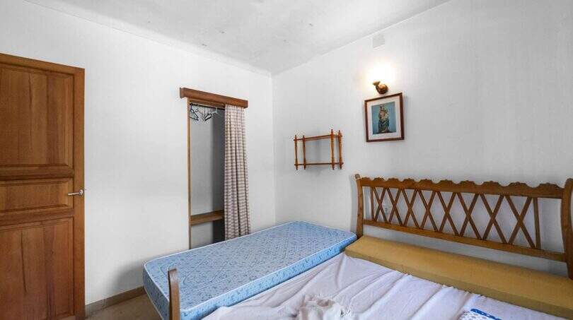 Schlafzimmer der Villa in Cala Figuera mit Doppelbett, Holzkopfteil, Einbauschrank und Wandleuchte