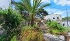 Verwilderter Garten mit Steintreppe, Palme und weißer Villa in Cala Figuera, Mallorca