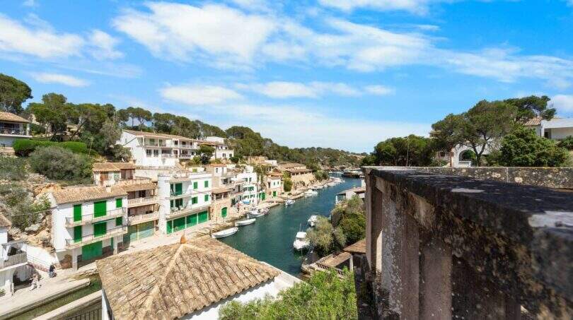 Blick auf den malerischen Hafen von Cala Figuera mit Booten, weißen Häusern und türkisblauem Wasser